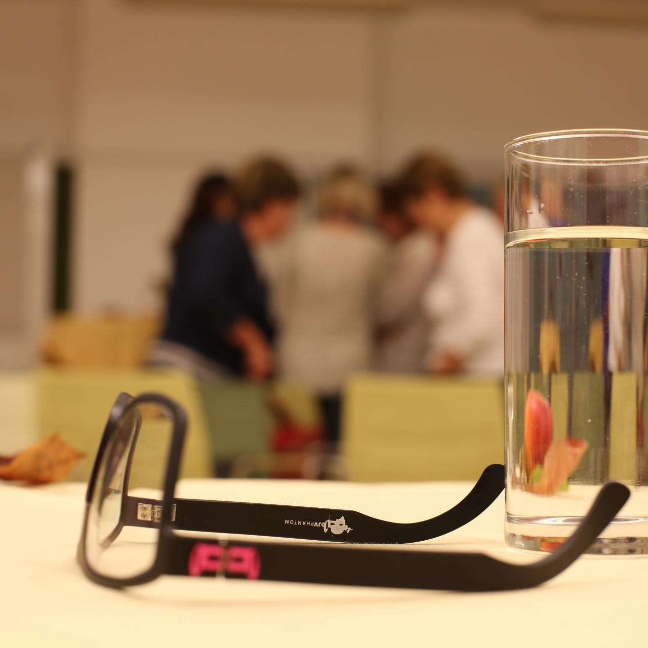 Am Tisch sind Lesebrille und Wasserglas